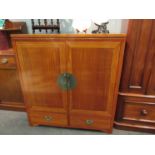 An Oriental style hardwood TV cabinet with cupboard door over two drawers,