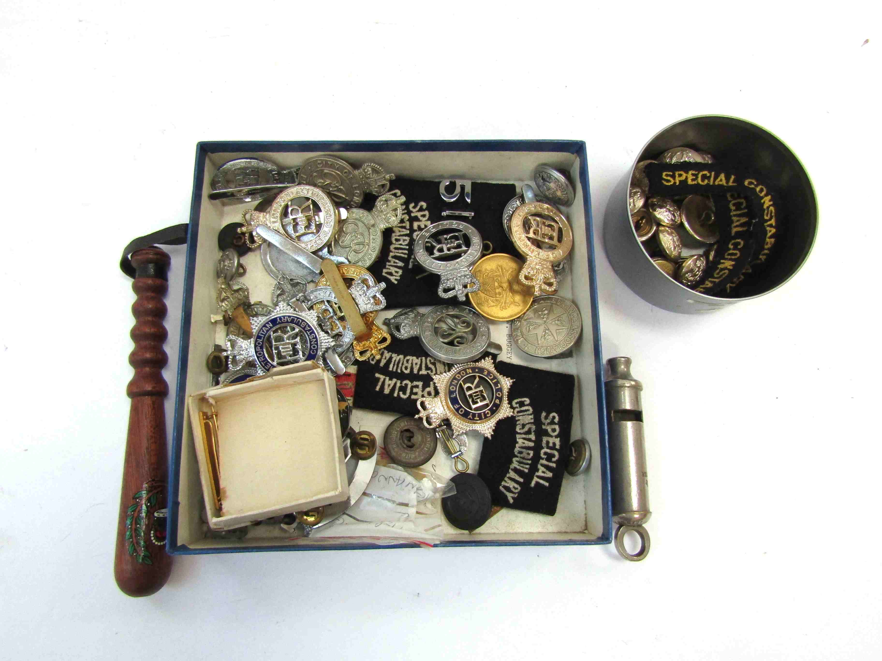A box containing a collection of Police badges and buttons including Metropolitan and City of