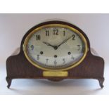 An early to mid 20th Century oak cased mantel clock with silvered Arabic oval dial,