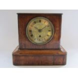 An oak mantel timepiece with French movement and silk suspension, engine turned dial,