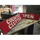 Two red signs painted "Open" and "Country Clutter"