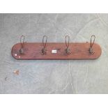 A set of four wire coat hooks on timber panel