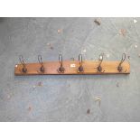 A set of six wire coat hooks on timber panel