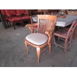 An Edwardian oak desk elbow chair with grey linen seat