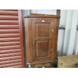 A Georgian oak and elm corner hanging cupboard, with key,