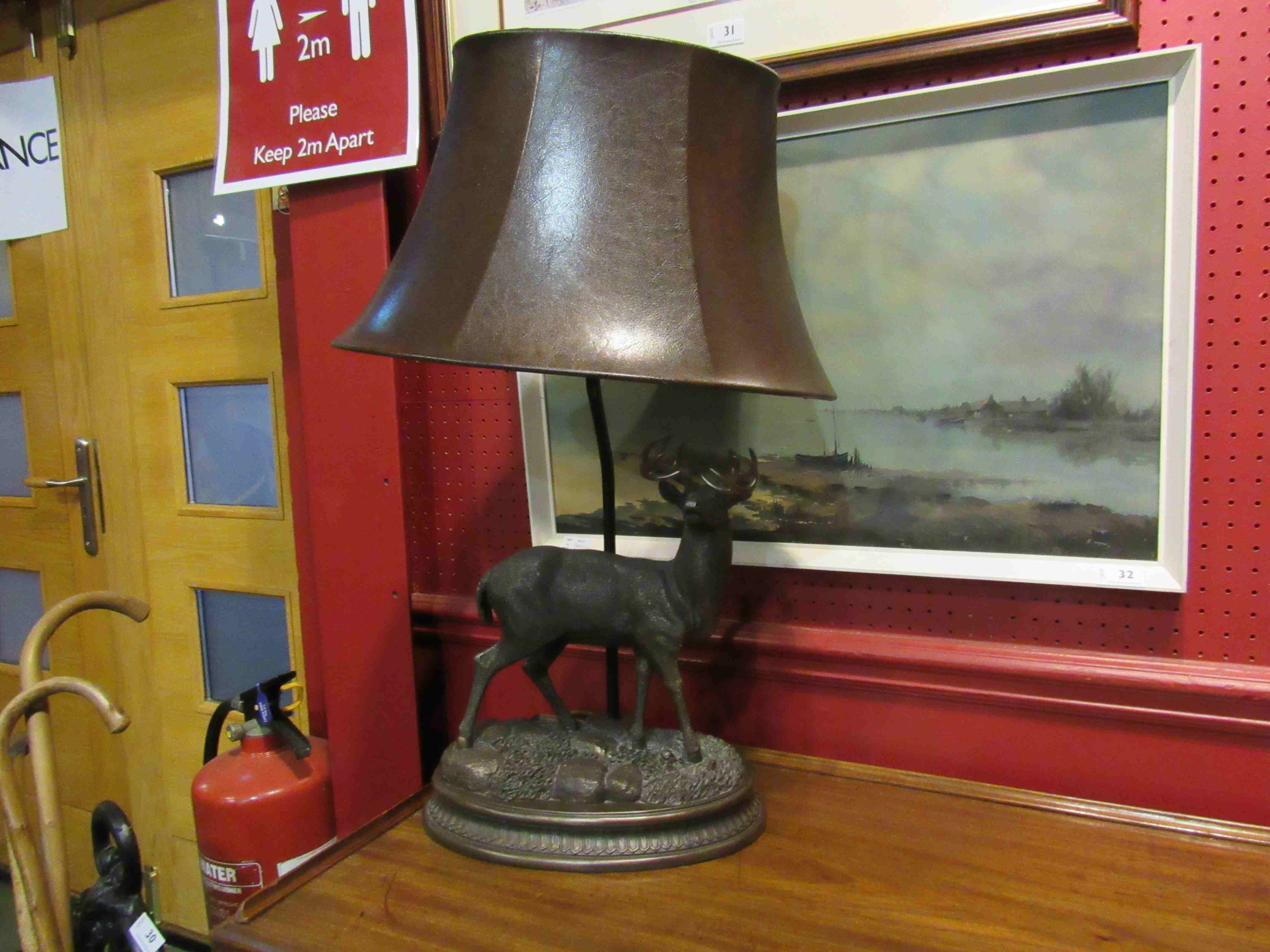 A bronzed resin table lamp base of stag form, leather shade,