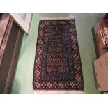 An Eastern black ground wool rug with central geometric field and borders in orange,