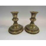 A pair of silver squat form candlesticks, dented, 12cm tall,