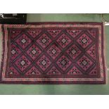 A dark red and blue ground rug with geometric borders and central diamond field,