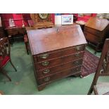 A Georgian oak bureau with fall flap and fitted interior over four graduating long drawers on