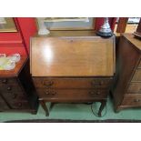 A 1930's oak bureau, fall front over twin drawers, shaped square legs,