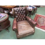 A late Victorian buttoned leather club fireside chair (worn)
