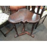 An Edwardian oak clover leaf top lamp table on turned and carved tri-legs with sledge feet base,