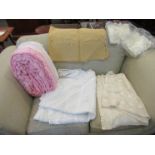 A box of table linens and a pink candlewick bedspread