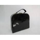 A vintage black patent vanity case with bottle contents, red interior,
