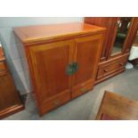 An Oriental style hardwood TV cabinet with cupboard door over two drawers,