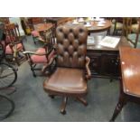 A button back leather swivel desk armchair with shepherd crook shape arms and brass stud decoration