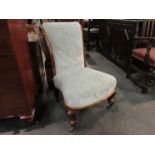 An early Victorian walnut nursery open armchair with carved acanthus leaf scroll back rest over