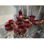 A ruby glass teaset with gilt and floral detailing
