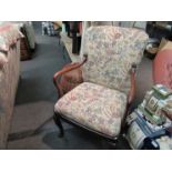 An Edwardian open arm desk chair with floral tapestry upholstery on cabriole legs