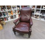 An early Victorian mahogany leather library armchair with turned and carved decoration over turned