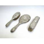 A silver three piece mirror and brush set decorated with birds and cherubs