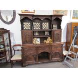 A Georgian style oak heavily carved dresser with shelved and cupboard back over three drawer,