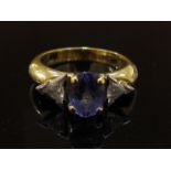 An 18ct gold ring, central oval tanzanite 1.34cts flanked by two trillion cut diamonds. Size N, 6.