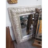 A metallic wall mirror, allover foliate design, bevelled glass,