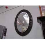 An oval carved oak mirror with acanthus border bevelled glass,