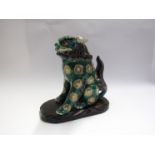 An Oriental ceramic figure of a temple dog green and gilt decoration on wooden plinth 25cm tall,