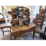 An Edwardian crossbanded mahogany breakfront dressing table the brass finials and tilting bevelled