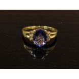 An 18ct gold tanzanite ring, the oval stone flanked by diamonds. Size R, 3.