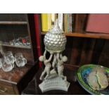 An ornate table centre piece, putti holding lidded bowl aloft,