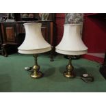 A pair of brassed table lamp bases with cream shades
