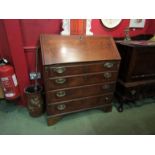 A Georgian oak bureau with fall flap and fitted interior over four graduating long drawers on