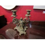 A brass twin sconce candlestick with lady playing musical instrument,