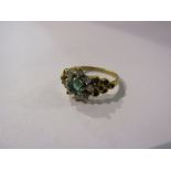 An 18ct gold emerald and diamond cluster ring.