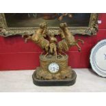 A gilt timepiece with figure holding rearing horses on associated base, Roman numerated dial,