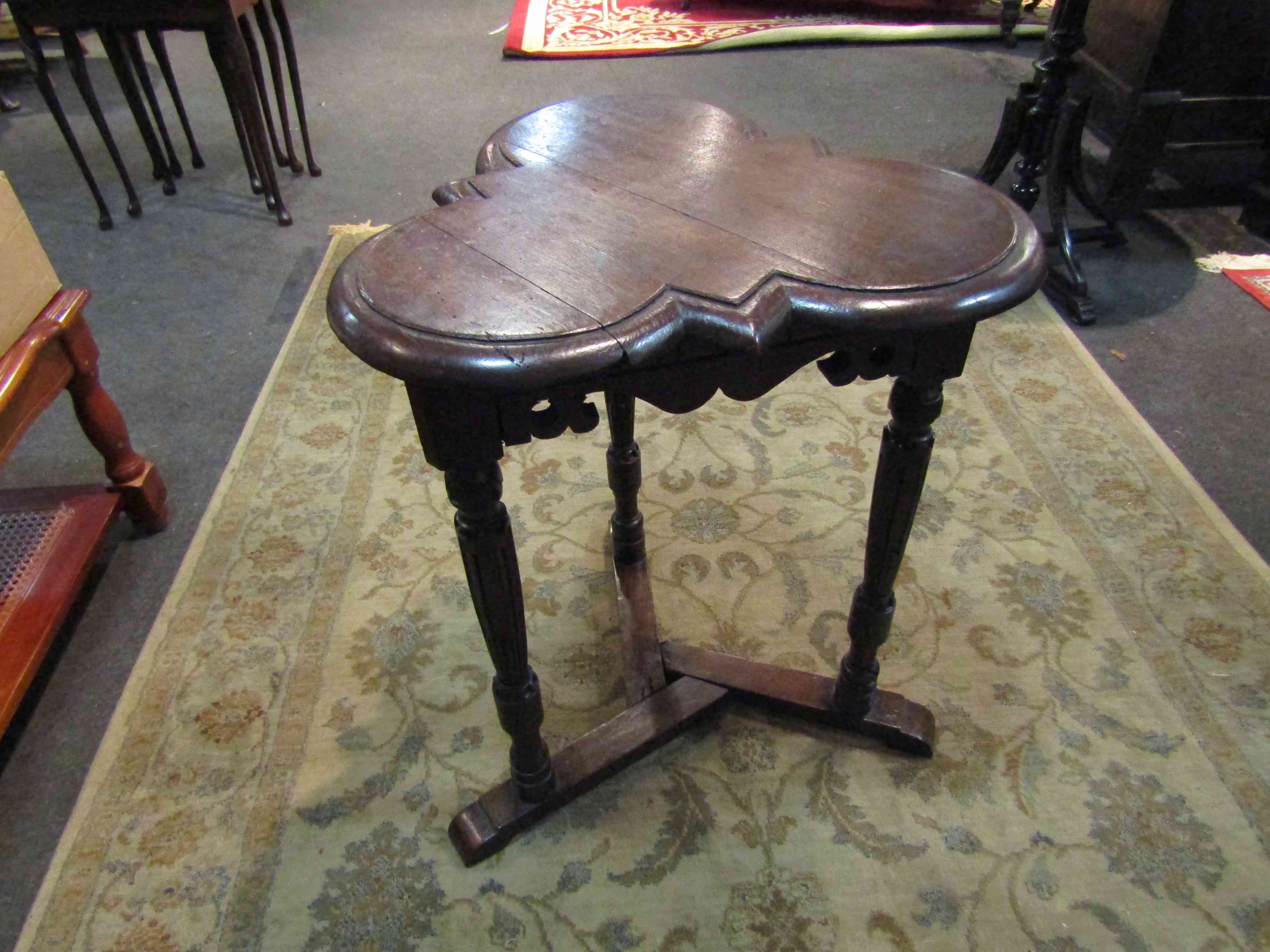 An Edwardian oak clover leaf top lamp table on turned and carved tri-legs with sledge feet base,