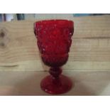 A pressed glass water goblet, the ruby red bowl with raised decoration,