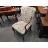 An Edwardian open arm desk chair with floral tapestry upholstery on cabriole legs