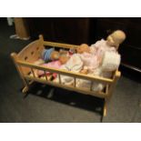 A beech doll's cot with various dolls including Baby Annabel, two porcelain and cloth bodies dolls,