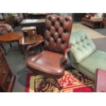 A button back leather swivel desk armchair with shepherd crook shape arms and brass stud decoration