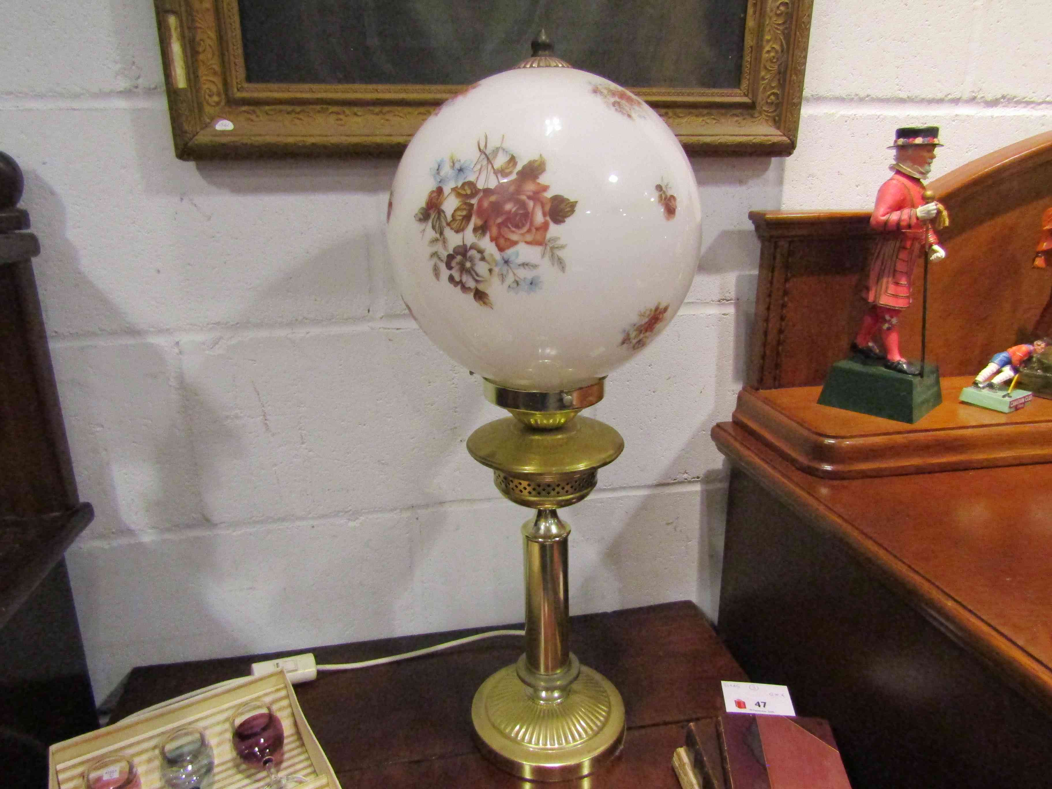 A brass effect table lamp base of oil lamp form with globular shade