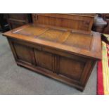 A 17th Century style oak three panel coffer with lined interior and key over stile feet,