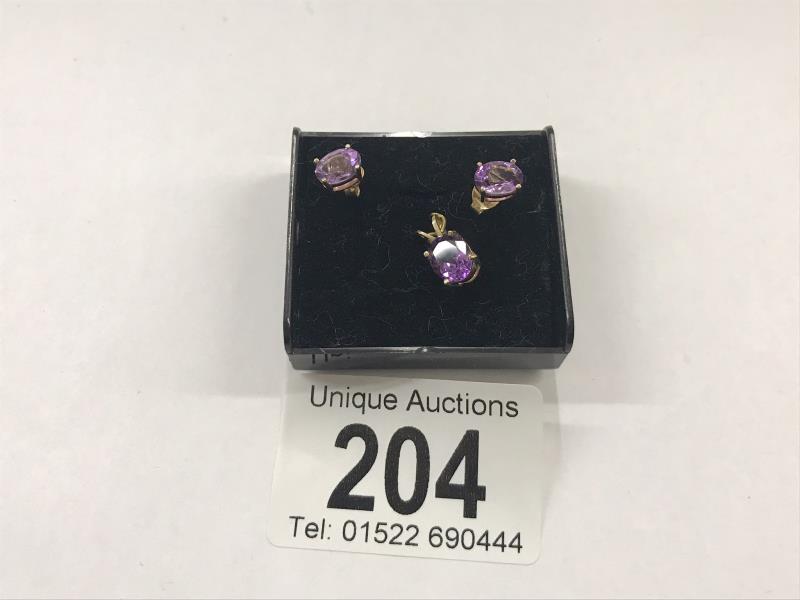 A 9ct gold pendant set amethyst with matching ear studs.