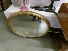 An oval gilt framed mirror.