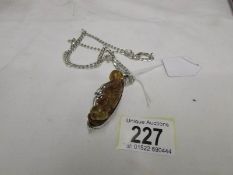 A silver pendant necklace of 2 rabbits caressing in amber.
