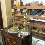 A pair of brass candlesticks with drip trays.